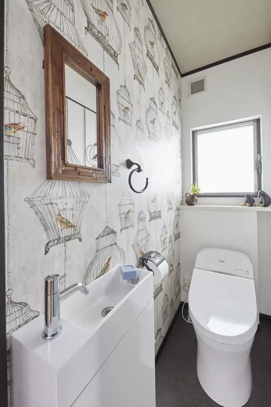 トイレのアクセントウォールに鳥かごのイラストが描かれた輸入壁紙を使用した実例